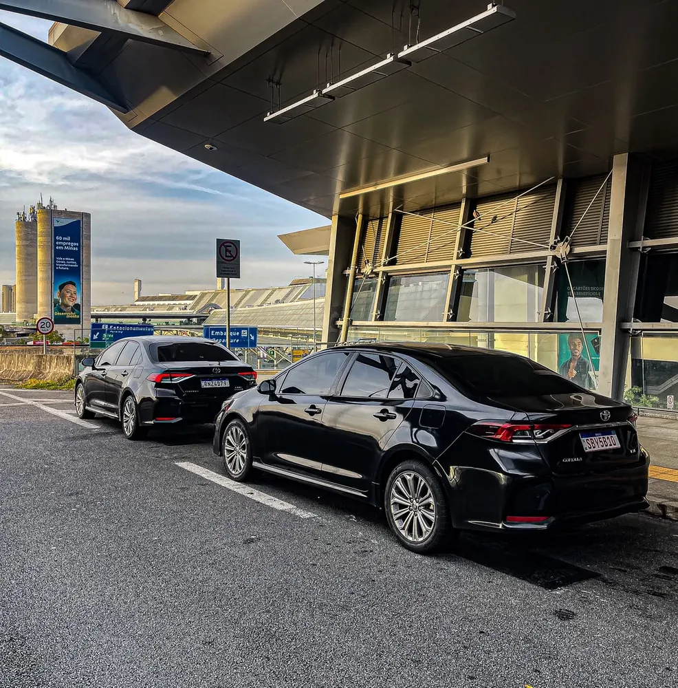Sedans executivos pretos da C.A. Transporte Executivo no embarque do Aeroporto de Confins